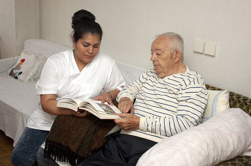 Nurse assisting elderly man with book